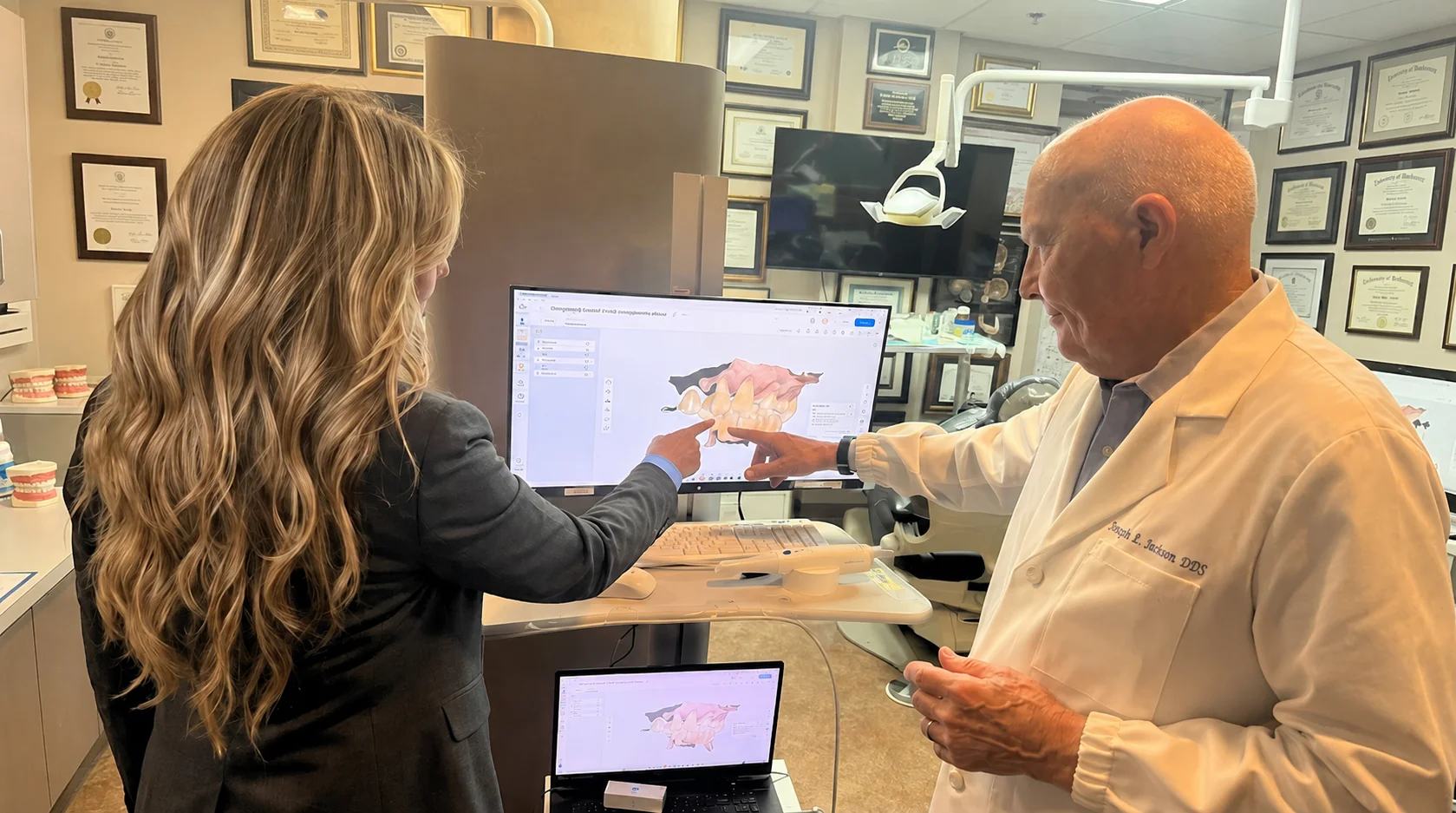 Dr. Douglas R. Maxson and a team member reviewing a 3D digital scan of a patient's case on a computer screen